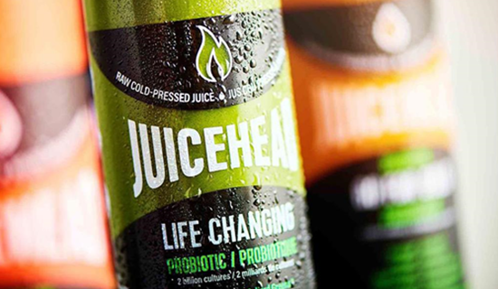 Close up of a plastic bottle filled with a green liquid and a logo that spell Juicehead
