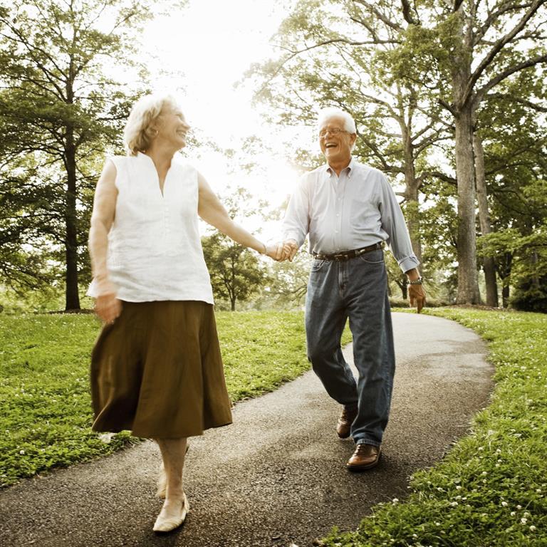 Elderly couple on walking path holding hands and smiling at each other