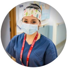 Female nurse wearing blue scrubs, a red Bruyère lanyard, and surgical mask and a headband