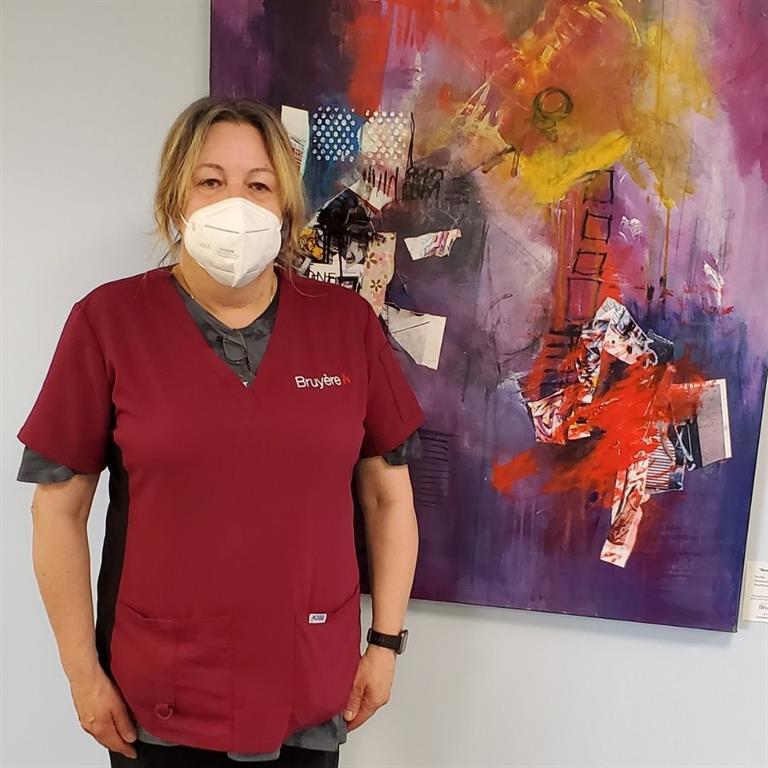 Photo of 5050 lottery winner Joanne Verdon standing in front of a piece of artwork 