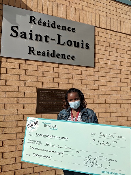 Astrid Diane Ciza pose avec son cheque devant la Résidence Saint-Louis