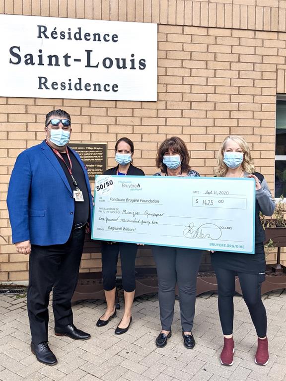 Guy Chartrand, Melissa Donskov, Monique Chartrand and Peggy Taillon posing with a large cheque in front of Saint-Louis Residence