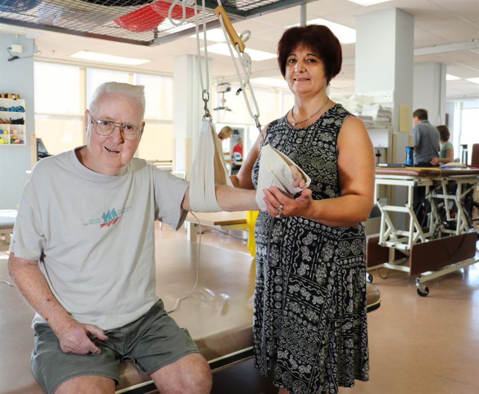 An elder man doing arm physio with a therapist